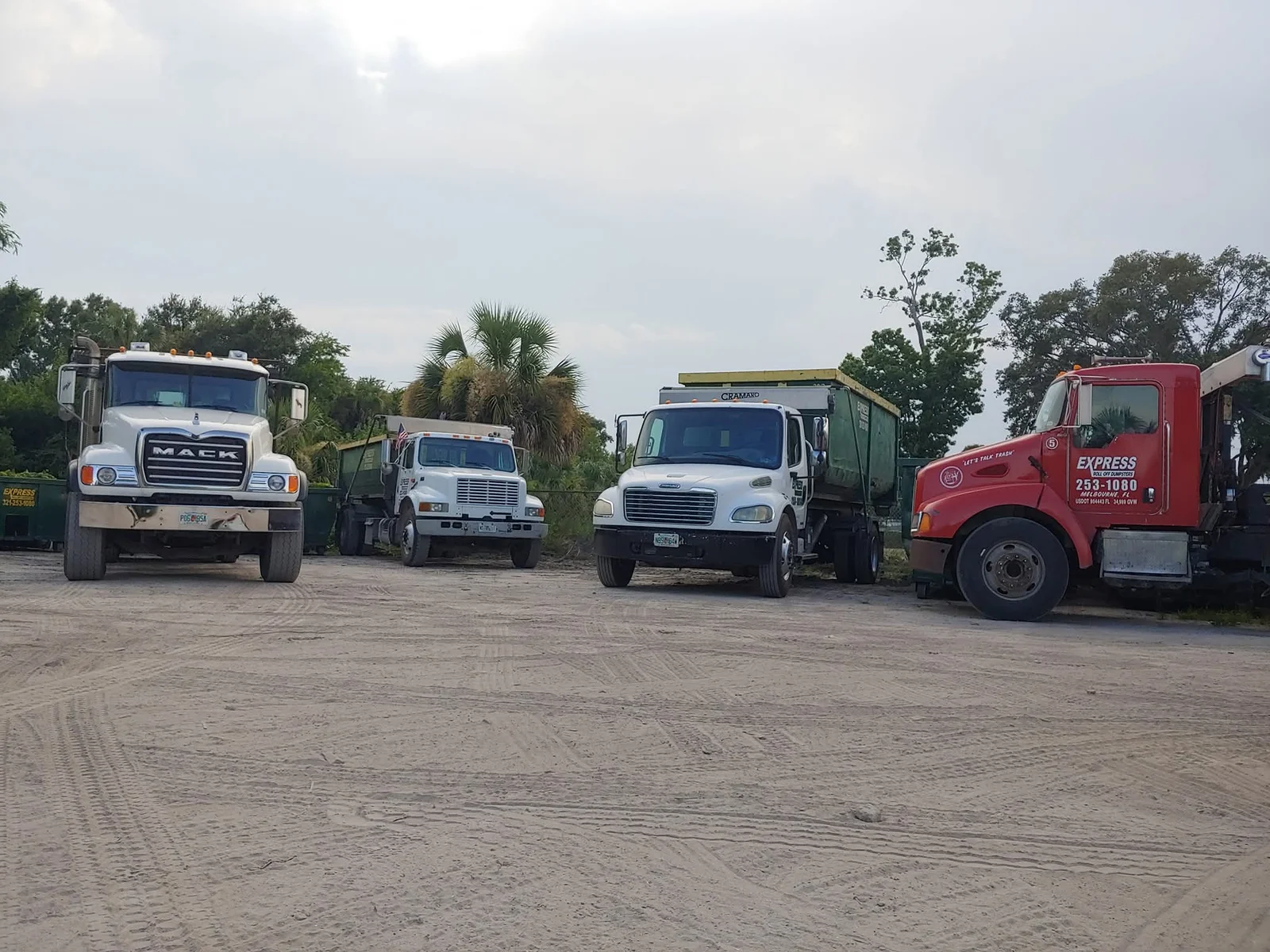 Retail renovation crew using roll off dumpster behind active shopping center during cleanup